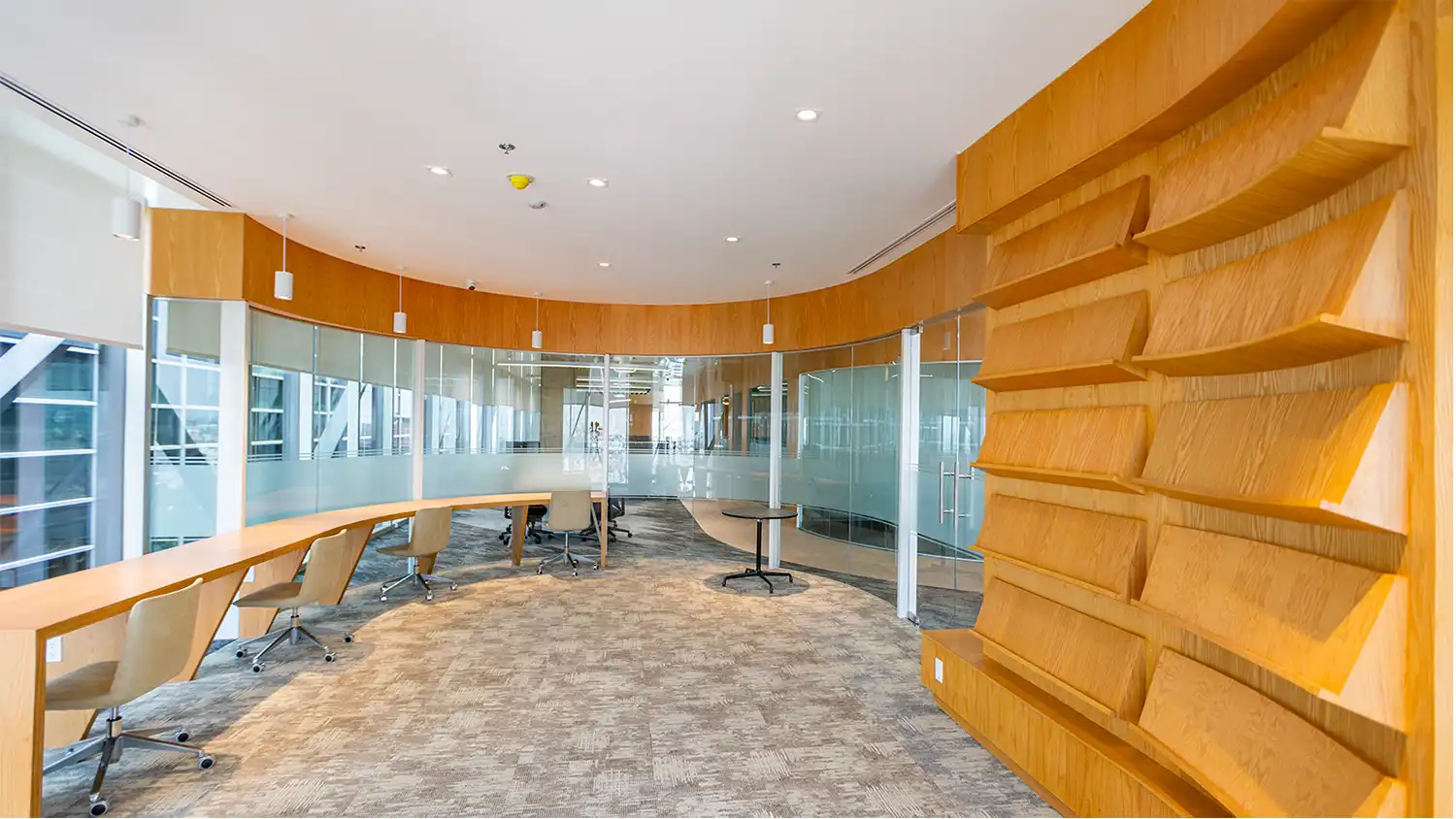 Área de biblioteca y zona de trabajo enfocada con estanterías de madera, diseño por VIDCON.