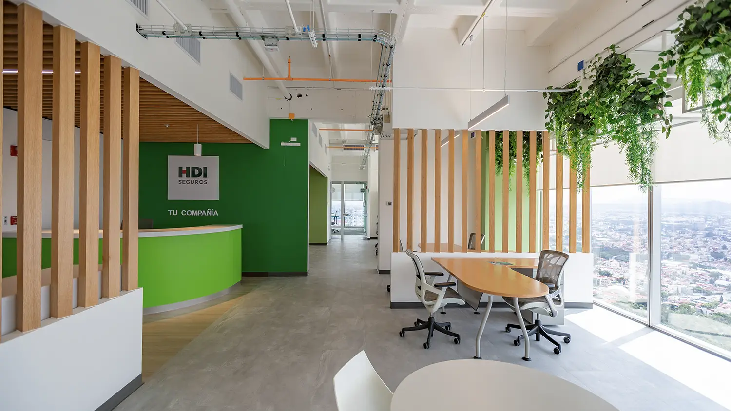 Recepción en oficinas de Puebla, diseño de interiores por VIDCON con paredes verdes y madera cálida.