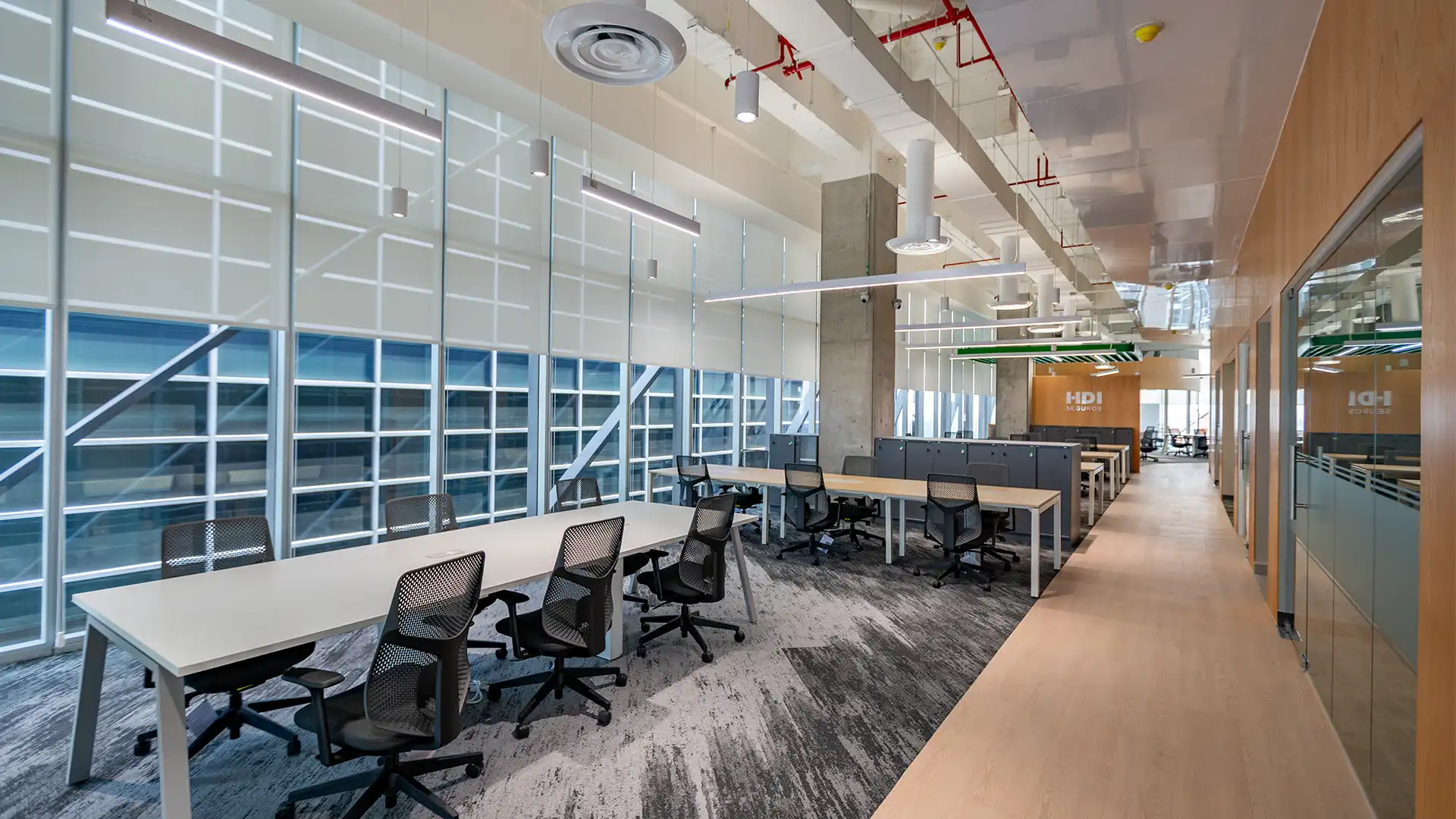 Zona de trabajo colaborativo con estaciones privadas y mesas modulares, diseñado por VIDCON.