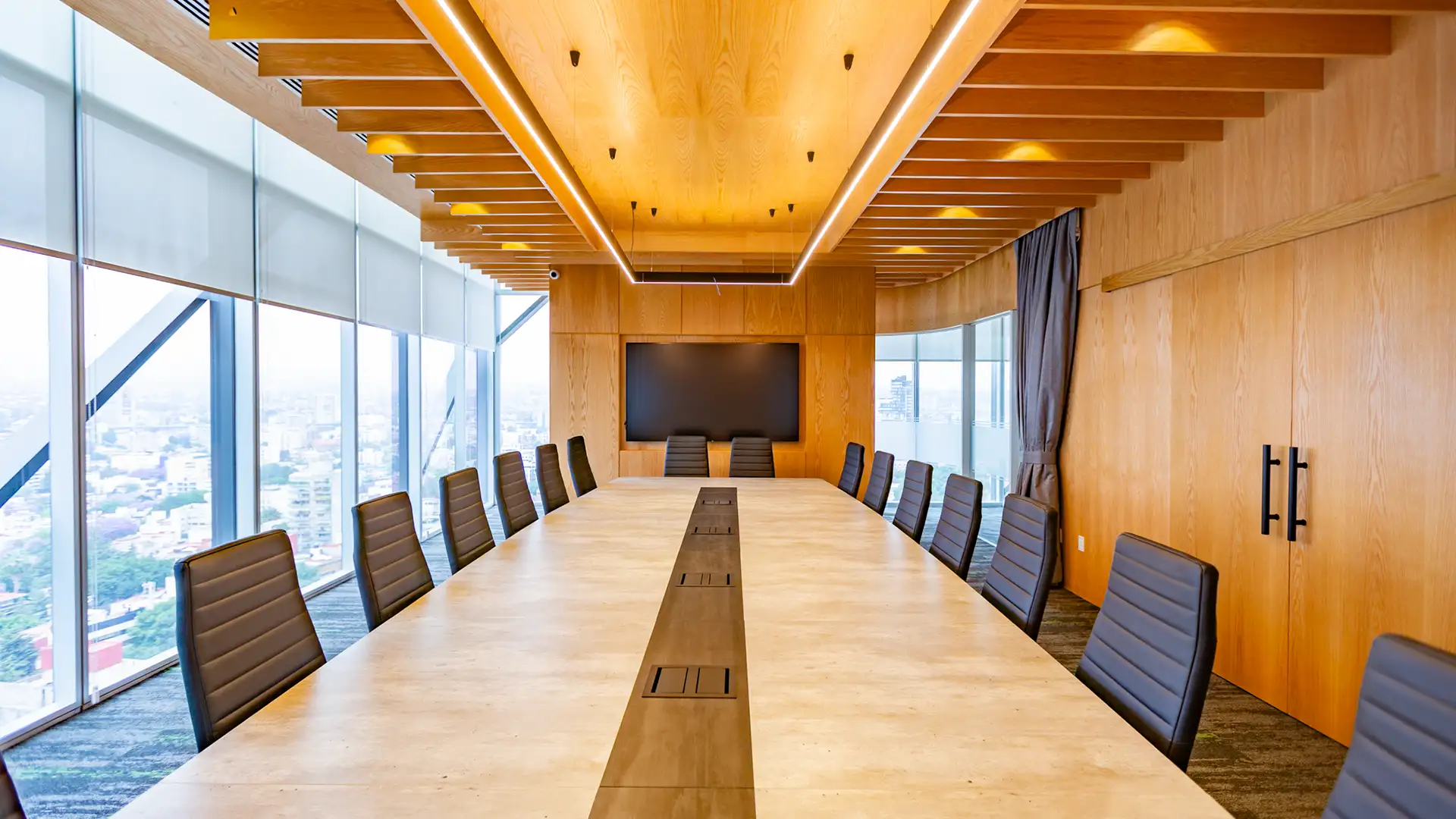 Sala de juntas corporativa en CDMX, diseño minimalista por VIDCON con mobiliario de madera y celosía iluminada.